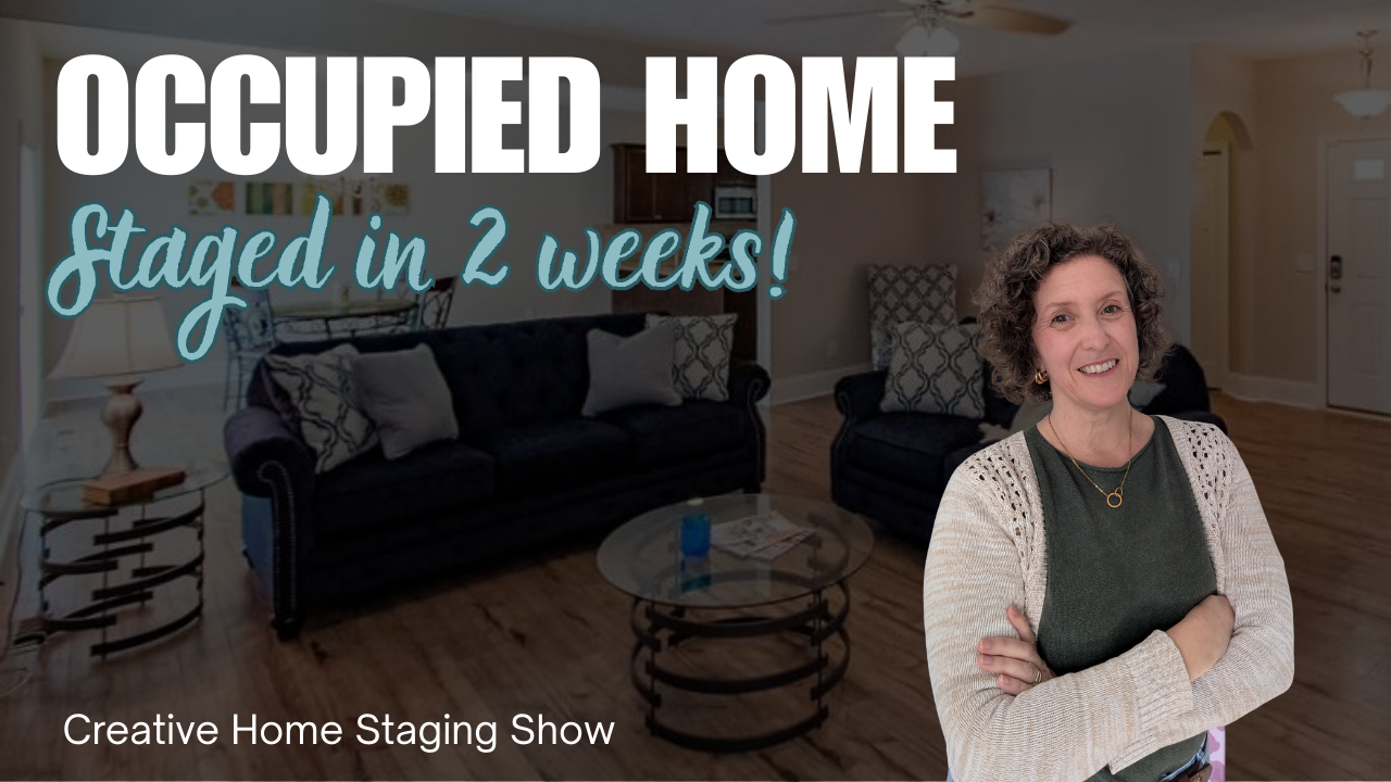 Kasia McDaniel, host of Creative Home Staging Show, is wearing a blue sweater with her hands by her head as if hiding. The background shows a teal painted dining room.